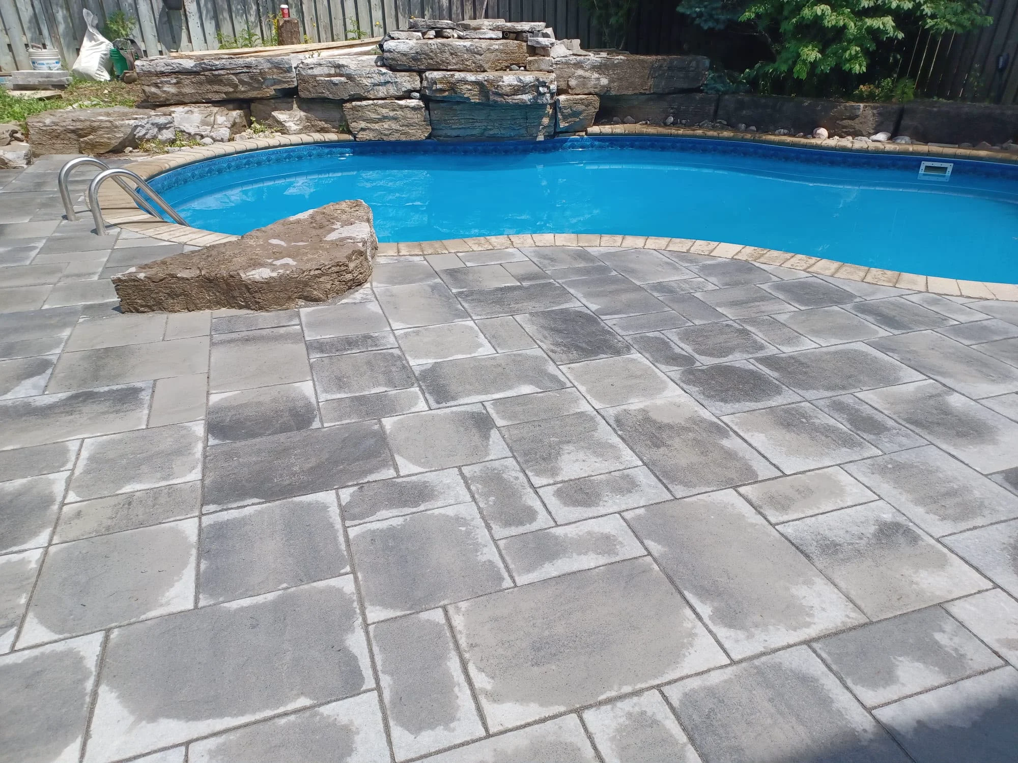 Poolside stone patio with a fountain by Credit Valley Landscaping